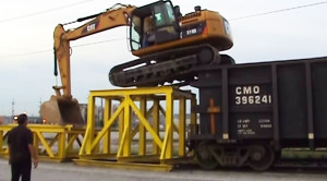 Yard Worker Climbs Onto Rail Car With An Excavator